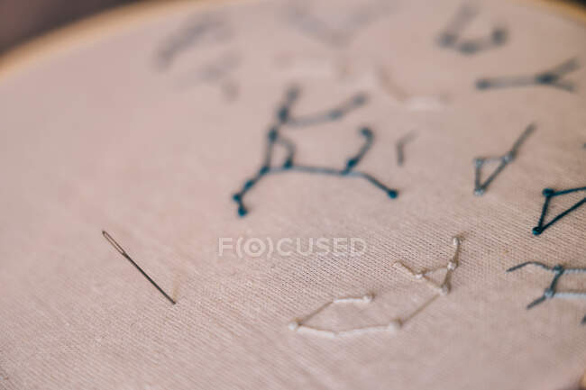 Bordado de estrellas constelaciones tejen en tela blanca en aro con aguja afilada - foto de stock