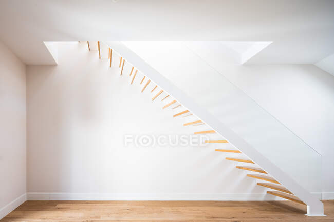 Escadaria de madeira acima do parquet perto da parede branca com sombra no edifício contemporâneo na luz do dia — Fotografia de Stock