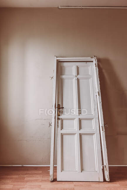 Porta in legno bianca con superficie squallida collocata nella vecchia stanza vuota durante il giorno — Foto stock