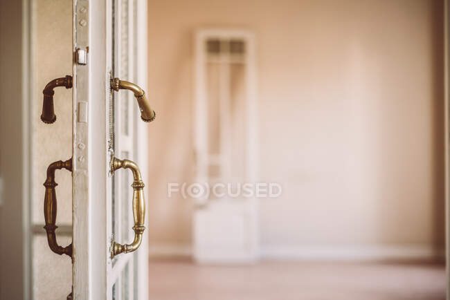 Puerta abierta de madera blanca a la antigua con asas ornamentales en estilo retro en apartamento vacío - foto de stock