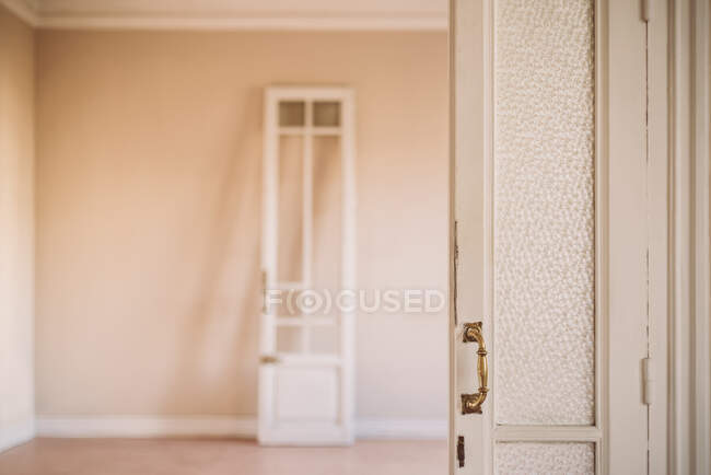 Puerta abierta de madera blanca a la antigua con asas ornamentales en estilo retro en apartamento vacío - foto de stock
