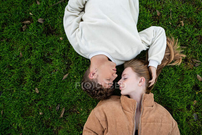 Visão aérea do jovem casal com olhos fechados descansando na grama — Fotografia de Stock