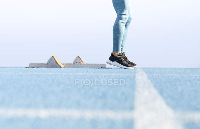 Ebenerdige Seitenansicht des Läufers, der in der Nähe der Startblöcke auf der Strecke steht und sich auf das Rennen im Stadion vorbereitet — Stockfoto
