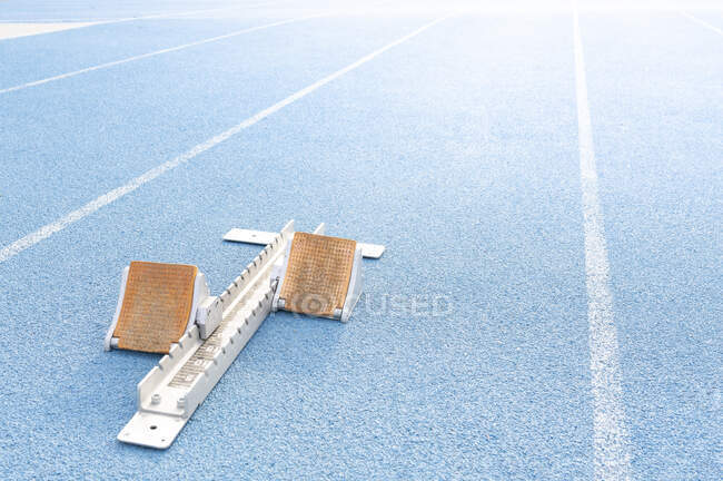 Alto ángulo de los bloques de salida colocados en pista azul en el estadio antes de la carrera - foto de stock