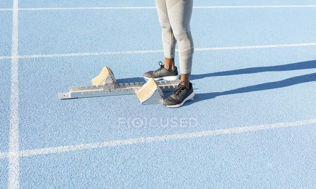 High angle of crop ethnic runner standing on track near starting blocks while preparing for race at stadium — Stock Photo