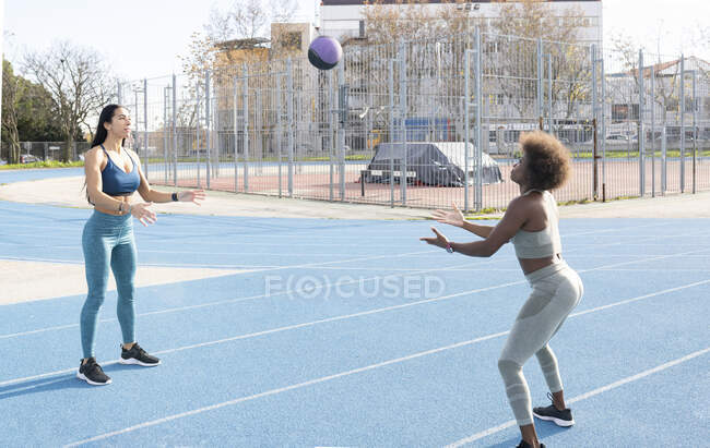 Sportive muscolose multirazziali lanciano palla medica mentre si allenano in pista allo stadio — Foto stock