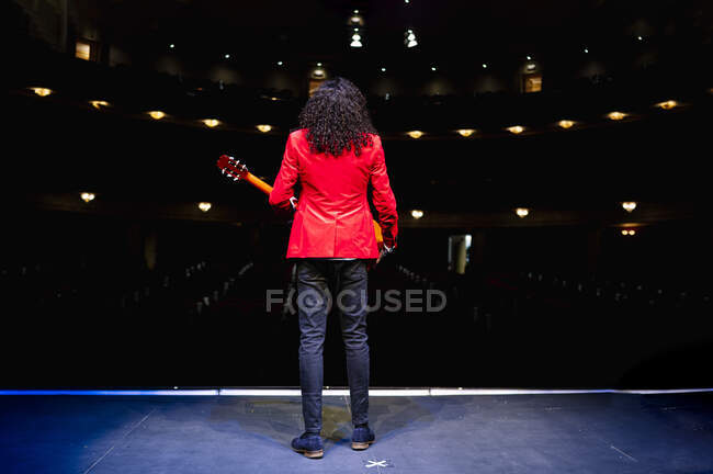 Повне тіло чоловіка-музиканта, що стоїть на сцені і грає на гітарі під час репетиції на сцені — стокове фото
