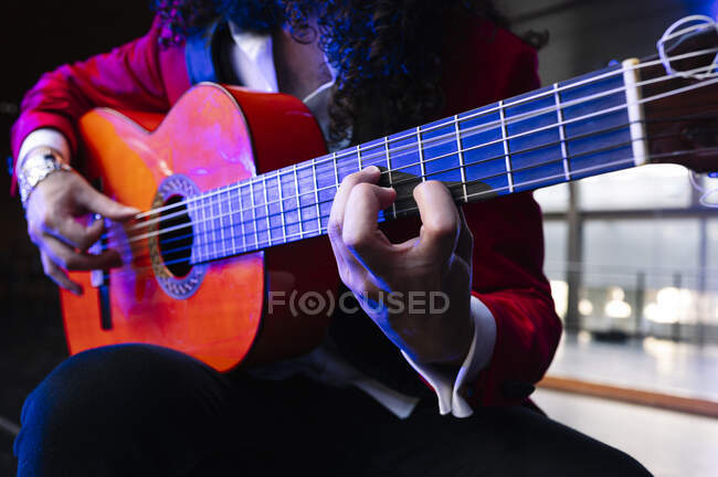 Crop músico masculino sentado na cadeira e tocando guitarra durante o ensaio no palco — Fotografia de Stock