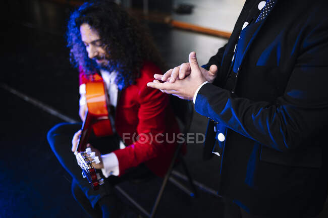 Musicista etnico maschile che tiene accordi su corde di chitarra mentre suona musica con l'artista al concerto — Foto stock