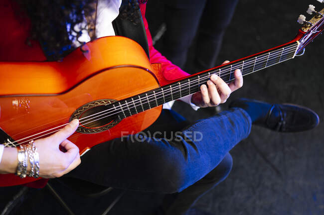 Ethnic male musician holding chord on strings of guitar while playing music with artist at concert — Stock Photo