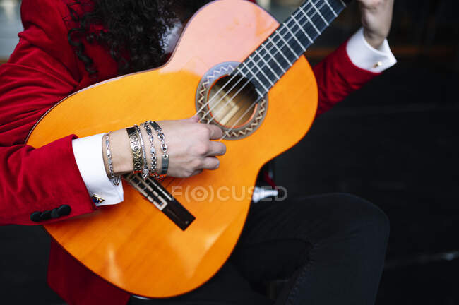 Crop musicista maschile seduto sulla sedia e suonare la chitarra durante le prove sul palco — Foto stock