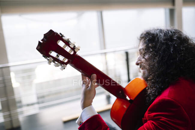 Músico masculino sentado na cadeira e tocando guitarra durante o ensaio no palco — Fotografia de Stock