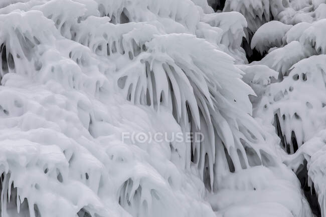 Ледяные брызги воды, покрывающие склон скалистой скалы возле озера Байкал в зимний день — стоковое фото
