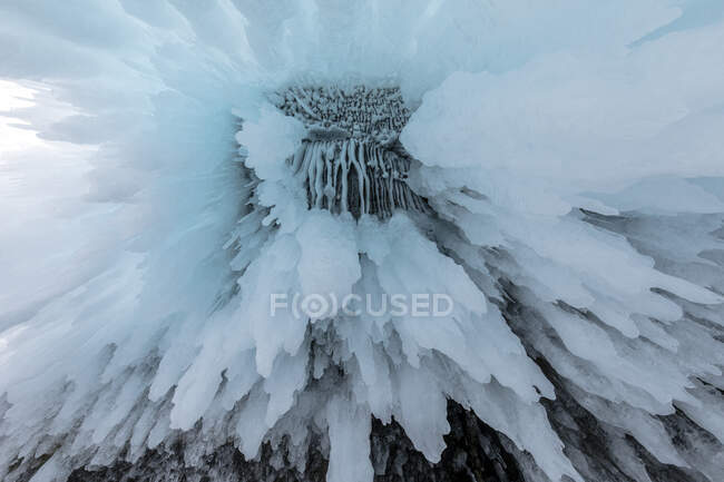 Desde abajo de enormes carámbanos colgando de la cueva rocosa cerca del lago Baikal en invierno como fondo abstracto - foto de stock