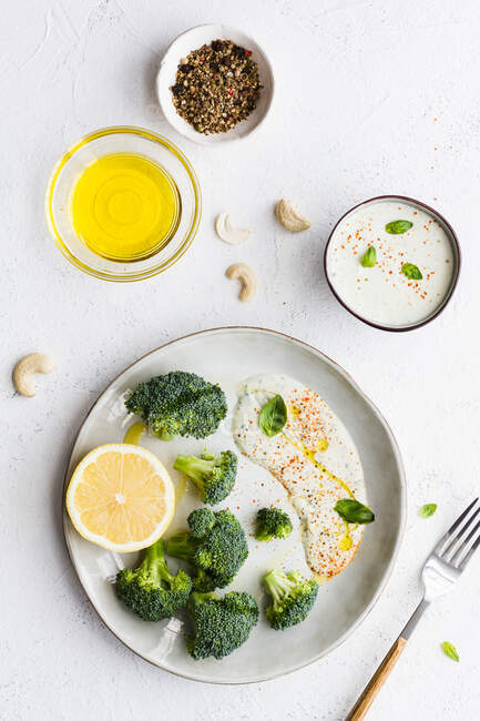 Vista dall'alto di gustosi broccoli con limone fresco e salsa vicino a ciotole con olio d'oliva e mix di spezie sul tavolo — Foto stock