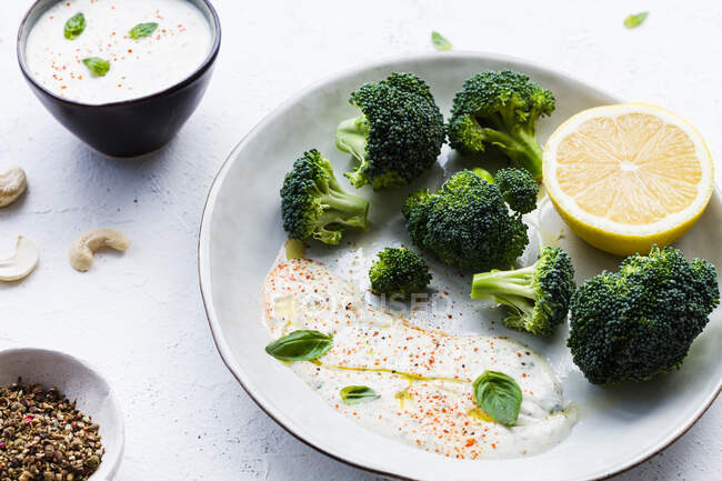 Draufsicht auf schmackhaften Brokkoli mit frischer Zitrone und Soße in der Nähe von Schüsseln mit Olivenöl und Gewürzmischung auf dem Tisch — Stockfoto