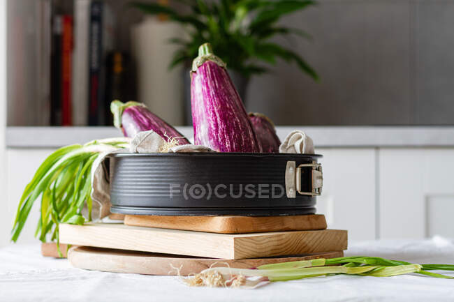 Berinjelas frescas com cebola verde colocadas na mesa para cozinhar o almoço vegetariano saudável em casa — Fotografia de Stock