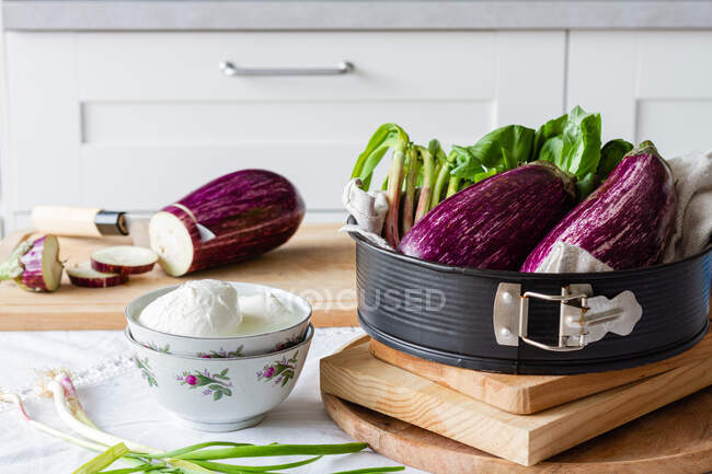 Bowl of mozzarella cheese with green onion and cut eggplant on chopping board for healthy lunch — Stock Photo
