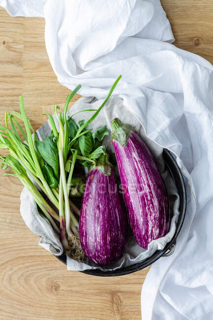 Свіжі баклажани з зеленою цибулею кладуть на стіл для приготування здорового вегетаріанського обіду вдома — стокове фото