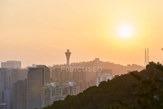 Peaceful view of contemporary metropolis with skyscrapers and residential buildings under orange sky in twilight — Stock Photo