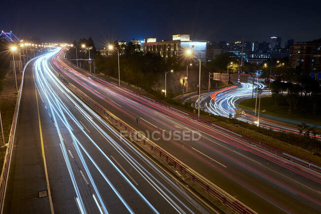 Довга експозиція зайнятої асфальтової дороги з автомобілями в сучасному міському мегаполісі вночі — стокове фото