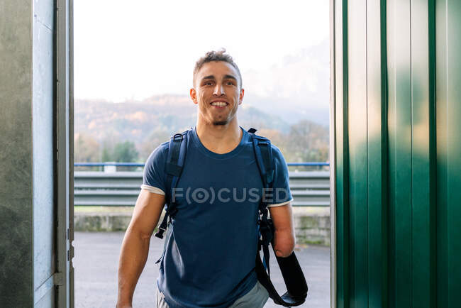 Young fit resilient cheerful handicapped sportsman walking into gym — Stock Photo
