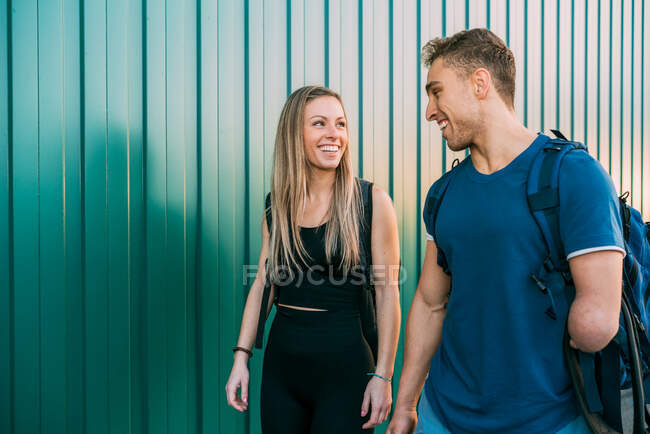 Jovens se encaixam esportista feliz e desportista deficiente andando no ginásio juntos olhando um para o outro — Fotografia de Stock