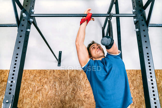 Юный спортсмен-инвалид тренируется на горизонтальной штанге во время тренировки в тренажерном зале — стоковое фото