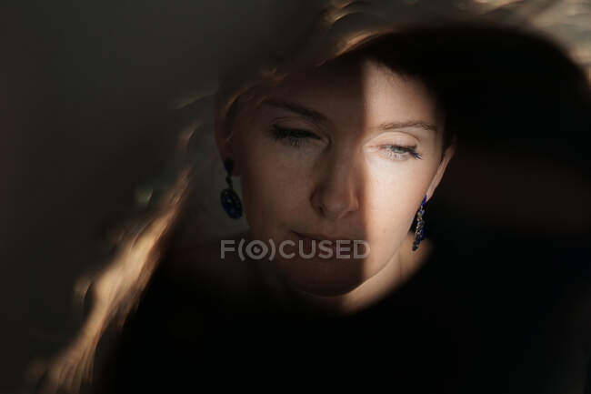 Through glass of peaceful thoughtful adult lady with short hair looking away on sunny day — Stock Photo