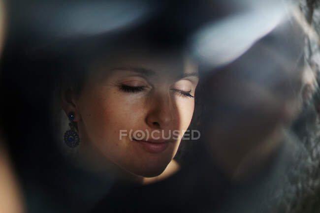 Durch das Glas einer friedlichen erwachsenen Dame mit kurzen Haaren, die an sonnigen Tagen mit geschlossenen Augen nachbildet — Stockfoto