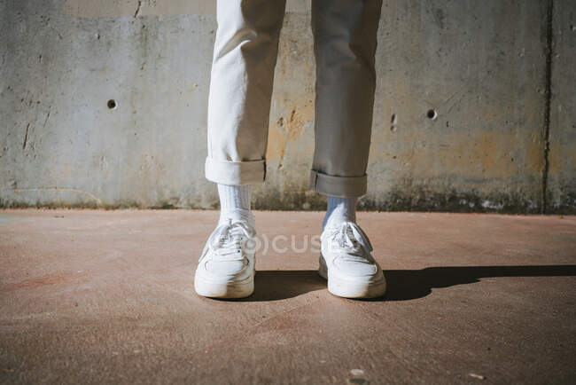 Сверху от урожая неузнаваемый модный парень в стильных кроссовках, стоя на улице в солнечный день — стоковое фото
