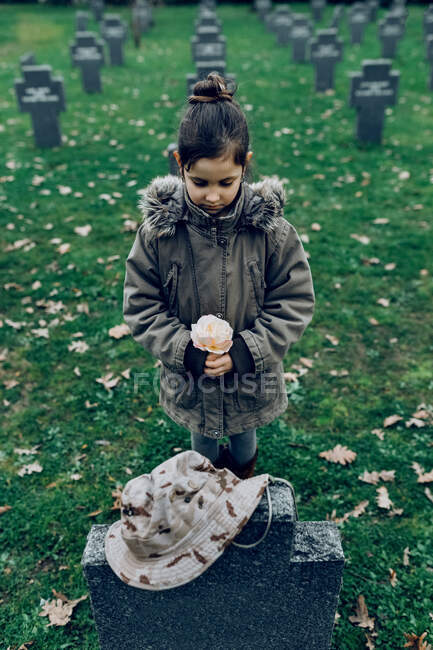 High angle of small kid mourning death of soldier fighting in war at graveyard — Stock Photo