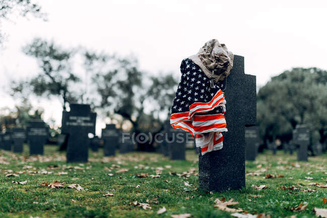 National American flag and army flag placed on gravestone in military cemetery on early autumn day — Stock Photo