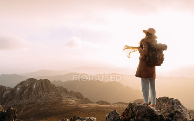 Обратный вид на неузнаваемого туриста, стоящего на камне и наблюдающего удивительные пейзажи горной долины в солнечный день — стоковое фото
