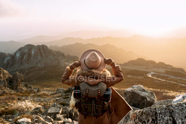Vista trasera de un excursionista irreconocible de pie sobre piedra y observando un paisaje increíble del valle de las tierras altas en un día soleado - foto de stock