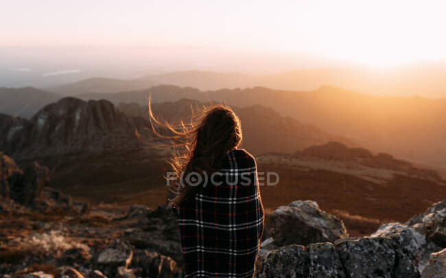Vista posteriore di escursionista irriconoscibile in coperta in piedi sulla pietra e osservando paesaggi incredibili della valle degli altopiani nella giornata di sole — Foto stock