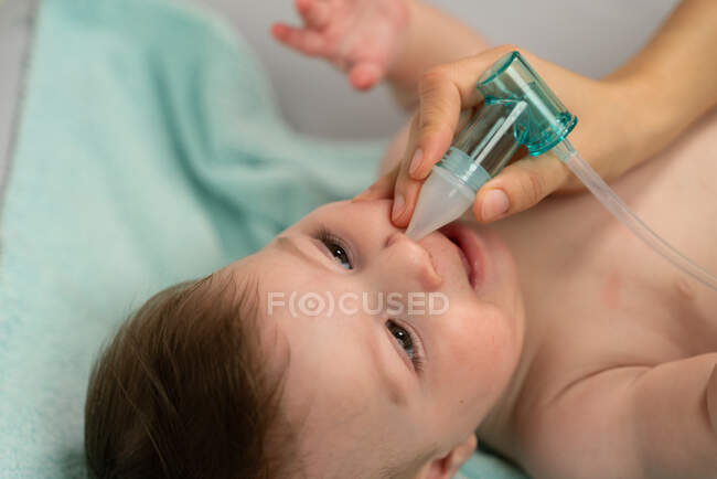 Crop caring mother placing suction machine into adorable baby nostril to remove mucus — Stock Photo