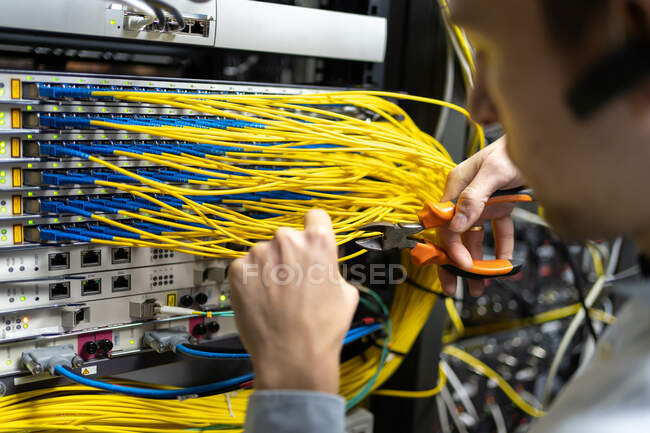 Technicien de culture mâle avec coupe-fils travaillant avec le système électronique de la salle des serveurs — Photo de stock