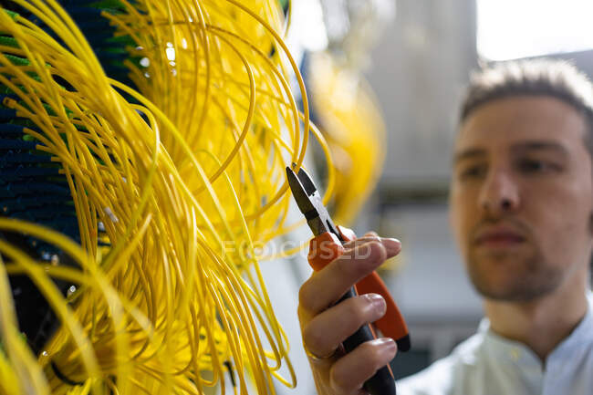 From below blurred male technician with wire cutters working with electronic system of server room — Stock Photo