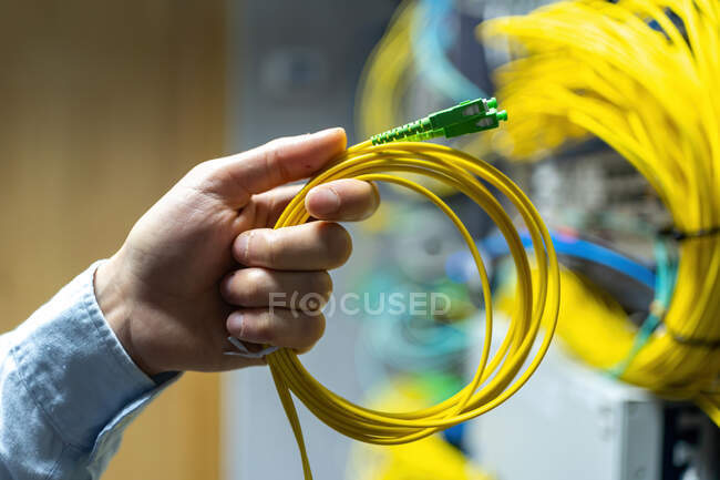 From below of crop anonymous man putting electronic cable in data system in communications room — Stock Photo