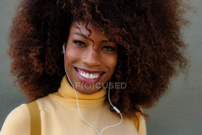 Черная женщина с афроволосами слушает музыку с рюкзаком на спине — стоковое фото