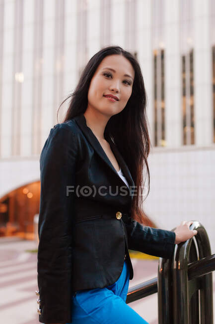 Side view of well dressed ethnic female entrepreneur walking on the street of megapolis and looking at camera — Stock Photo