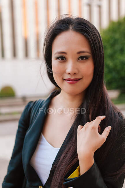 Delighted ethnic female entrepreneur wearing smart casual clothes standing in street and looking at camera at daytime — Stock Photo