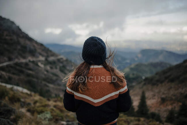 Взгляд назад молодая женщина смотрит в сторону, стоя на грубом высокогорье в облачный мрачный день — стоковое фото