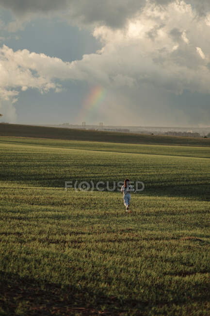 Voltar vista mulher correndo na grama verde no vale — Fotografia de Stock
