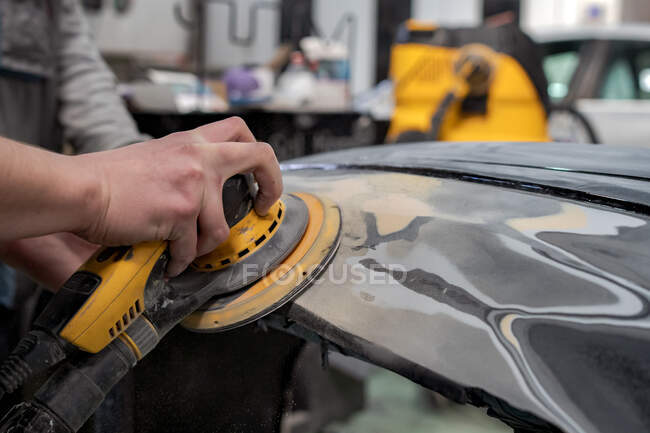 Crop anonyme männliche Mechaniker mit Maschine zum Polieren Auto während der Vorbereitung Automobil für die Lackierung in der Werkstatt — Stockfoto