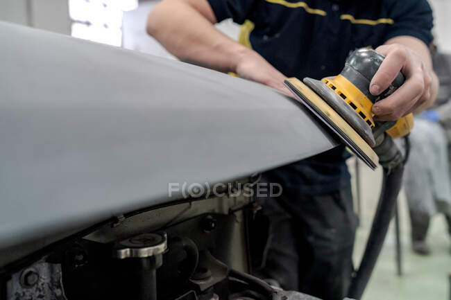 Crop anonyme männliche Mechaniker mit Maschine zum Polieren Auto während der Vorbereitung Automobil für die Lackierung in der Werkstatt — Stockfoto