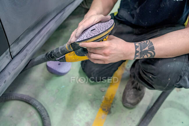 From above of anonymous crop male master with buffing machine preparing for polishing car in service — Stock Photo