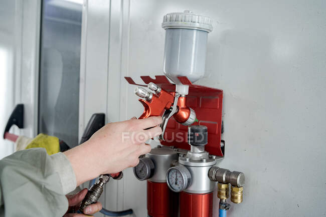 Crop unrecognizable male technician taking modern spray gun for painting car in service — Stock Photo