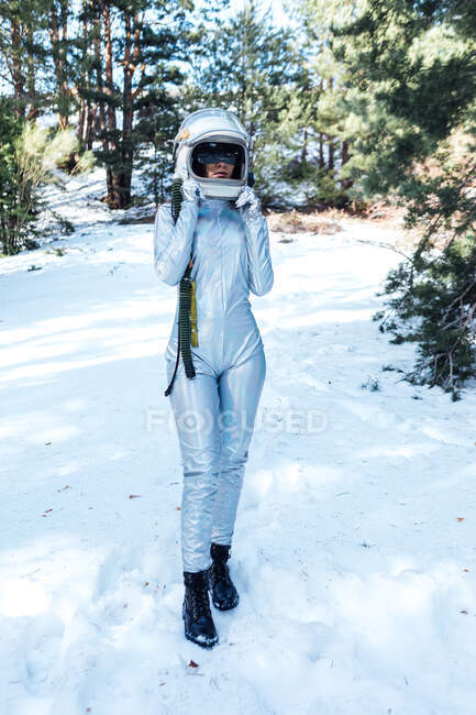 Konzentrierte, bis zur Unkenntlichkeit unkenntliche junge Astronautin in Raumanzug und Helm steht im verschneiten Wald — Stockfoto
